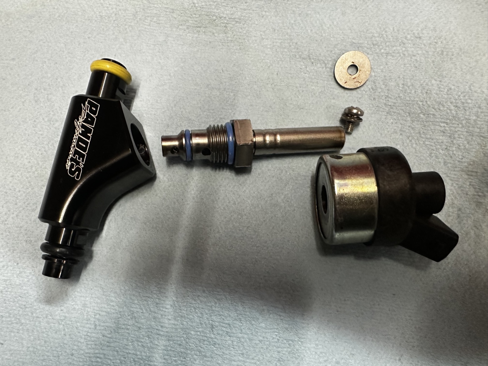A fuel injector disassembled on the bench, showing the internal valve, seals, and hardware