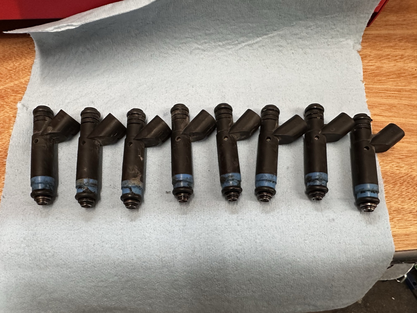Set of eight Siemens fuel injectors before service, covered in grime with degraded O-rings